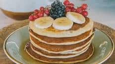 Fluffy pancakes with maple syrup, banana, blackberries and redcurrants